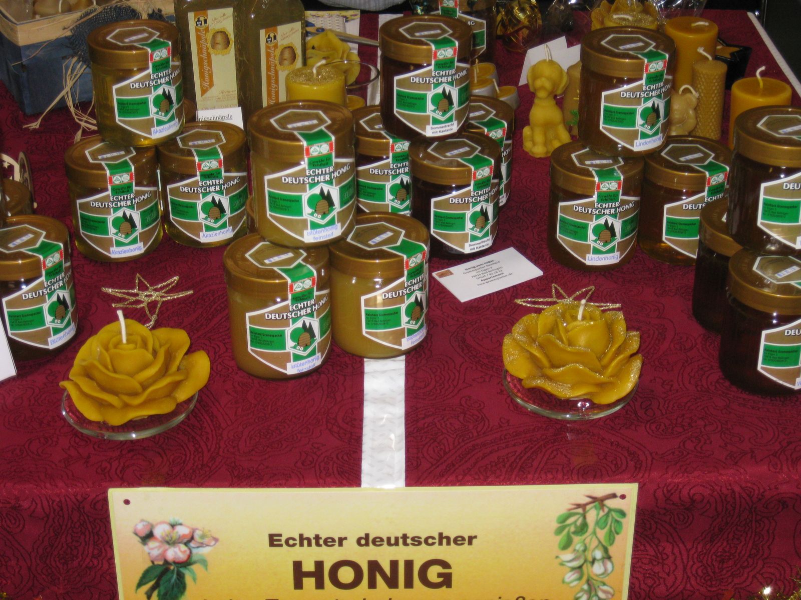 Honiggläser und Bienenwachskerzen in Rosenform auf einem Verkaufstisch